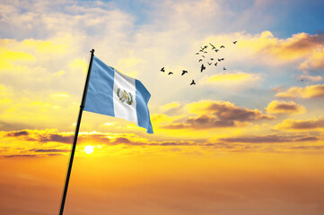 Waving flag of Guatemala against the background of a sunset or sunrise. Guatemala flag for...