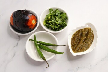 Homemade roasted tomato sauce or chutney served in a small ceramic dish on white background along...