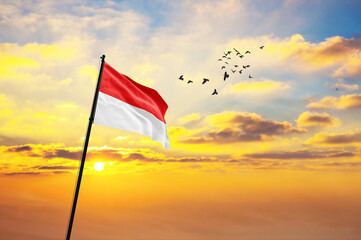 Waving flag of Indonesia against the background of a sunset or sunrise. Indonesia flag for Independence Day. The symbol of the state on wavy fabric.