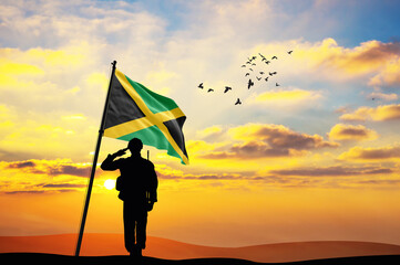 Silhouette of a soldier with the Jamaica flag stands against the background of a sunset or sunrise....