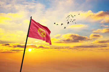 Waving flag of Kyrgyzstan against the background of a sunset or sunrise. Kyrgyzstan flag for...