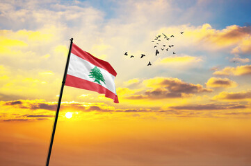 Waving flag of Lebanon against the background of a sunset or sunrise. Lebanon flag for Independence Day. The symbol of the state on wavy fabric.