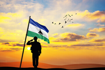 Silhouette of a soldier with the Lesotho flag stands against the background of a sunset or sunrise. Concept of national holidays. Commemoration Day.