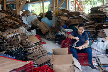 Obraz premium Young Hispanic Woman Removing Tape for Cardboard Recycling in Warehouse