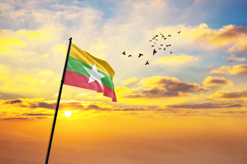 Waving flag of Myanmar against the background of a sunset or sunrise. Myanmar flag for Independence...