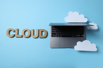 Laptop with paper clouds on a blue background, place for text