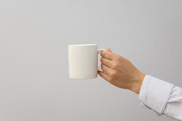 A woman holds a white cup in her hands