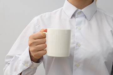 A woman holds a white cup in her hands