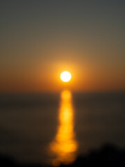Defocused photo of the moment when the sun sets on the sea, blurred image of the sun sets on the sea. A golden yellow light shone on the sea.