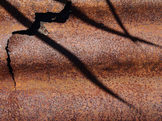 Image of dirty rust on an old galvanized sheet covered with the shadow of grass.