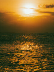 Picture of the atmosphere of the sun going down over the sea. The golden yellow light of the sun reflects off the sea.