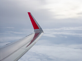 Airplane wing above the cloudy sky.