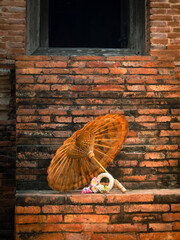 Picture of traditional handmade flower garlands and umbrella rest on the ancient brick floor. and the background is an old brick wall.