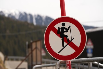 A no ski climbing sign prominently displayed against a backdrop of distant mountains and a metal...
