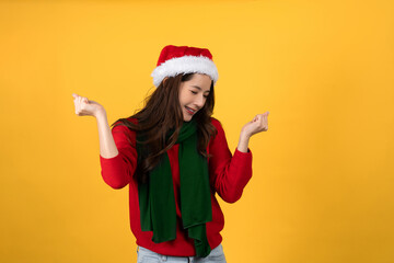 Beautiful happy Asian woman in red Christmas sweater and hat. She is excited and clenches both...