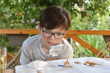 Happy child digging the dinosaur and having fun with archaeology excavation kit. Boy plays and learns, Dig the dinosaur from archeology kit