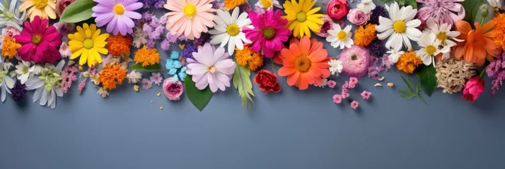 Foto auf Glas Assorted colorful spring flowers creating a vibrant border on a blue background © olga_demina