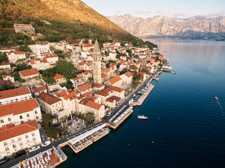 Fototapeta na wymiar Perast promenade with outdoor restaurants on the piers by the sea. Montenegro. Drone