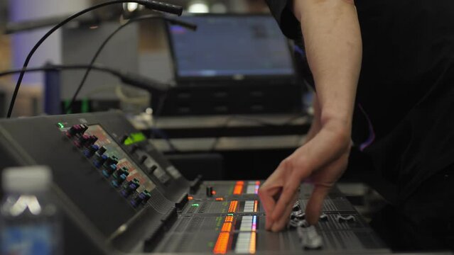 Man moves lever on sound amplifier control panel in sound record studio closeup. Audio director adjusts track with digital equalizer at workplace