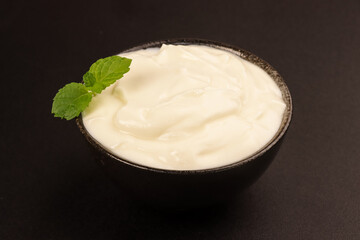 Yogurt in a Black Bowl Isolated on Black Background