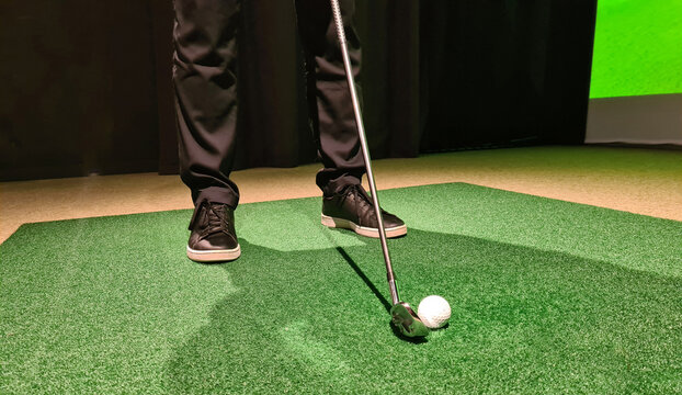 Male golfer plays golf indoors on golf simulator closeup