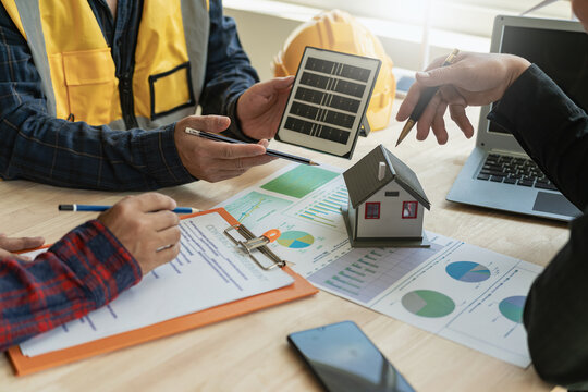 Meeting of engineers in modern office with solar cell samples and wind turbine models Creativity, innovative alternative energy design