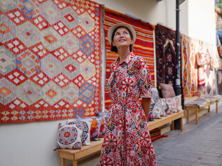female summer travel to Antalya, Turkey. young asian woman in red dress walk through old town Kalechi , female tourist traveler discover interesting places and popular tourist traditional carpet