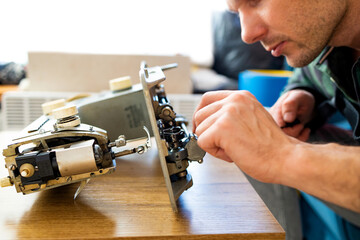 Repairman master is testing old disassembles sewing machine in workshop repairing it sitting at...