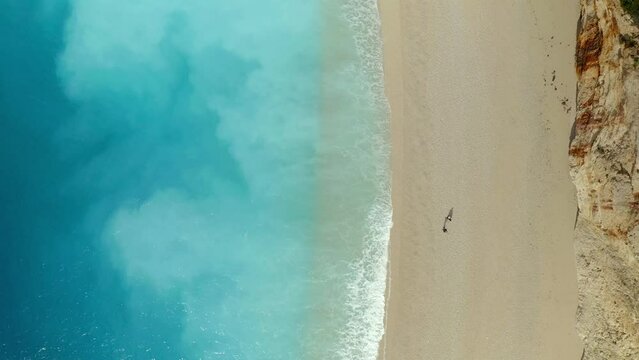 Drone aerial top view of couple walking on iconic Porto Katsiki beach in Lefkada island with turquoise water, in Greece