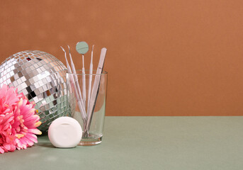 Dental tools, floss container, flowers and a glowing disco ball. Copy space for text.