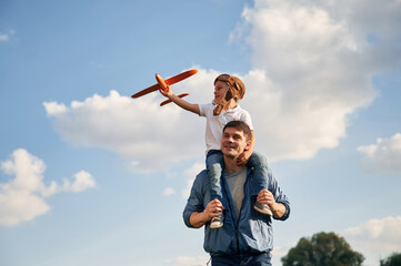With aviator glasses, playing with toy plane. Father and little son are having fun outdoors