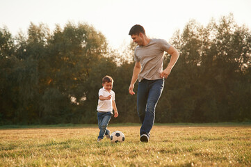 Activity, running and playing soccer. Father and little son are playing and having fun outdoors