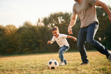 Learning how to play soccer. Father and little son are having fun outdoors