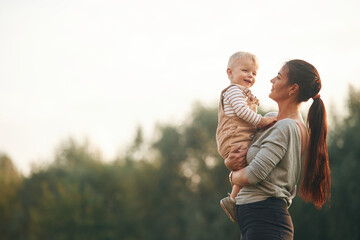 On the field. Mother is with her little baby son are outdoors together