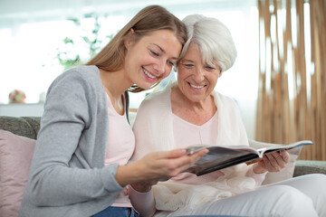 elderly woman looking at magazine with young woman