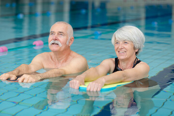 elderly couple following exercise movements in swimming pool