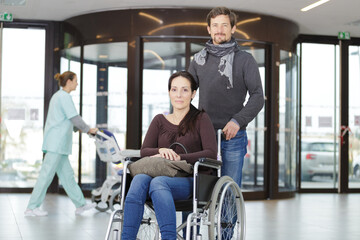 man taking care of woman in wheelchair indoors