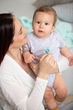 young happy mother holding her baby at home