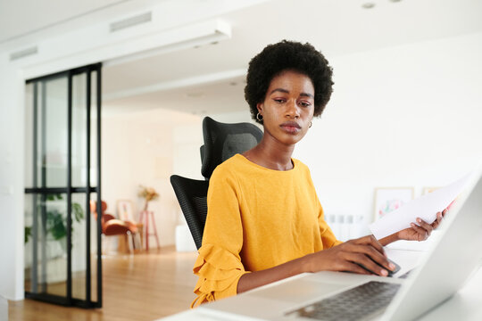 Environmental portrait of a businesswoman. diligent young professional woman evaluates reports at her sleek workspace, embodying focus and dedication in a contemporary office setting.