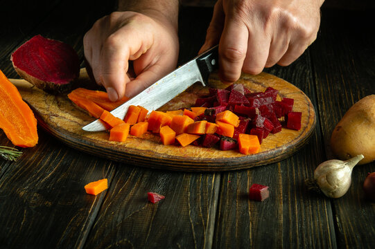 The chef is preparing a vegetable dish on the kitchen table. The process of preparing Vinaigrette on a dark background