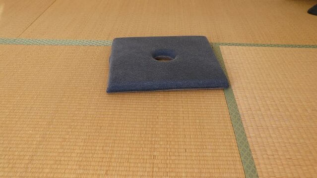 和室の座布団の上にあぐらをかいて座る男性