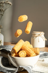 Mini waffle cookie rolls flying over a plate