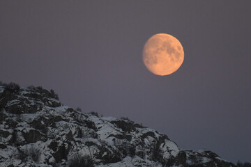 A near full moon is slowly creeping behind a mountain along the norwegian coast on an early winter...