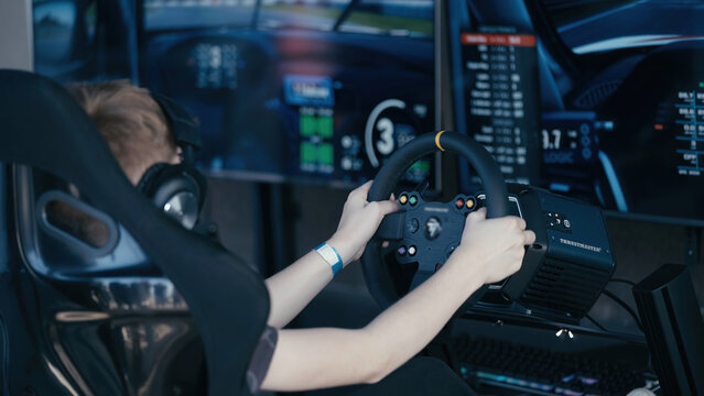 Young boy driving in a racing simulator surrounded with monitors