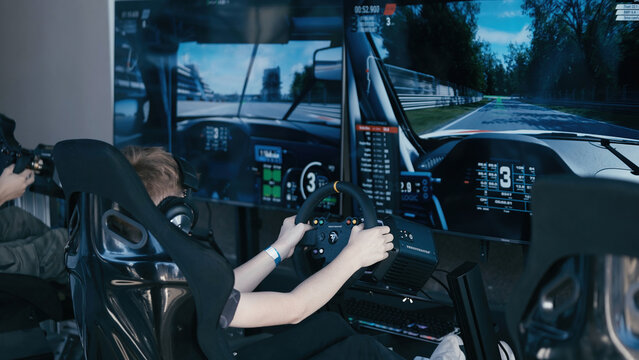 Young boy driving in a racing simulator surrounded with monitors