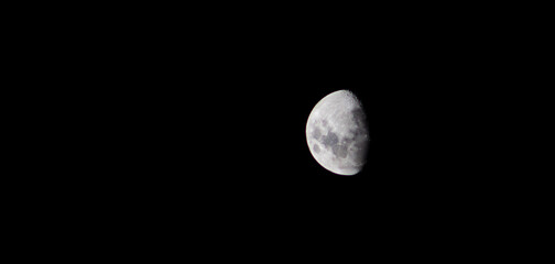 Three-quarter moon against a black night sky.