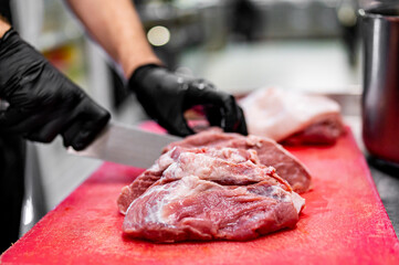 Chef Butcher cutting beef meat with knife on kitchen