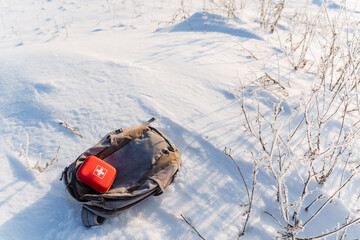 First aid kit is on the backpack in winter in the snow on a hike, red first aid kit, trekking in...