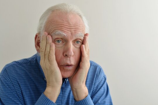 Facial portrait of an elderly gray-haired shocked man with an expressive look stunned by sudden news.
