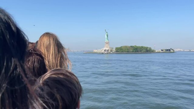 People observing and photographing with their mobile phone from a boat the famous and fabulous Statue of Liberty of the United States of America, located on Liberty Island in New York City.